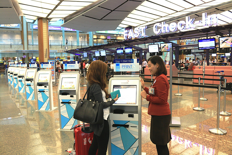 A woman checking in at the Fast and Seamless Travel (FAST) counter at Changi Airport